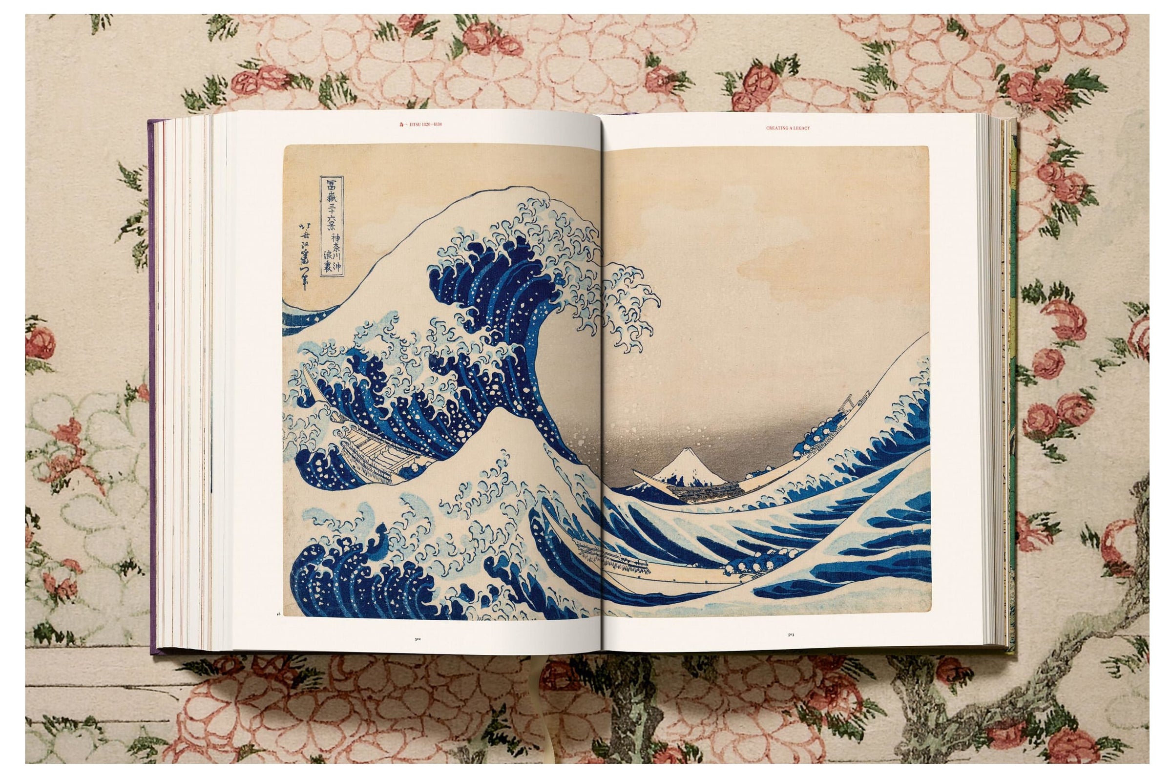 Open book displaying a famous artwork of a wave with Mount Fuji on a decorative floral background.